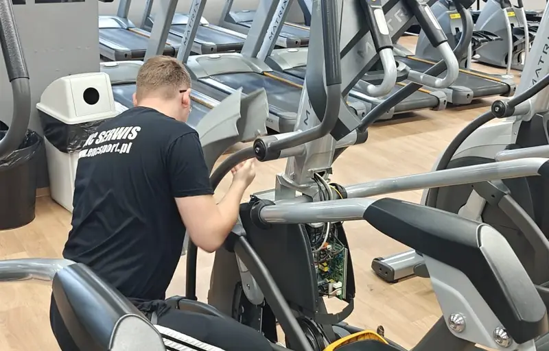 Serwisant ENC SERWIS naprawia orbitrek w klubie fitness